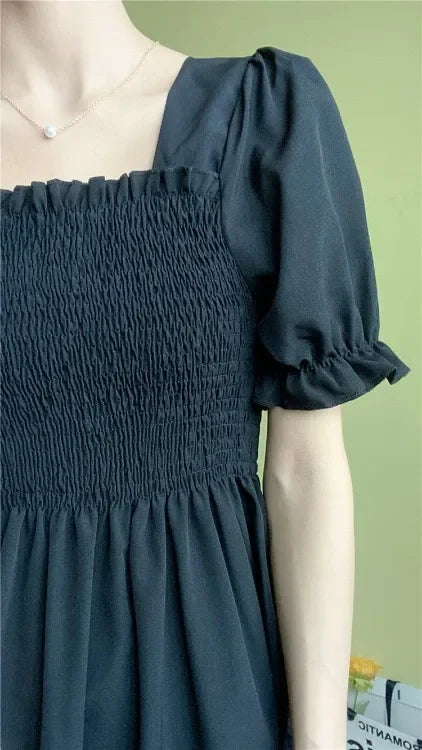 Chiffon A-line dress in black with smocked bodice and short puff sleeves.