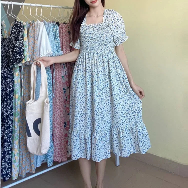 Blue floral chiffon dress with elastic waist, short sleeves, pleated A-line on model; rack of several dresses