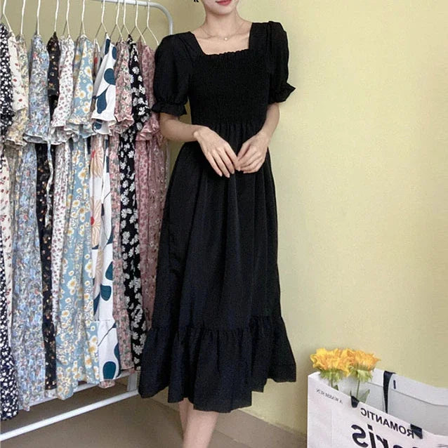 Black chiffon dress with elastic waist, short puff sleeves, A-line midi; rack with several patterned dresses